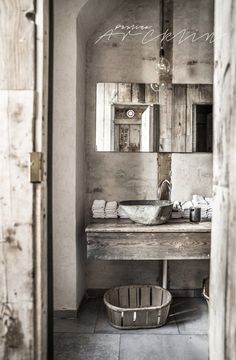 a bathroom with a sink, mirror and bucket in the corner next to it's door