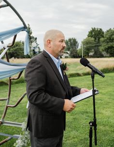 a man standing in front of a microphone holding a piece of paper while wearing a suit