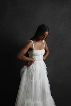 a woman in a white dress standing against a black background