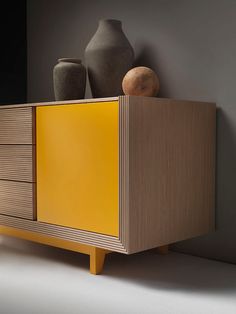 a yellow cabinet with two vases on top and another one in the back ground