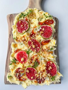 a pizza topped with cheese and fruit on top of a wooden cutting board