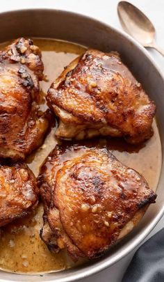 four pieces of cooked chicken in a pan with gravy