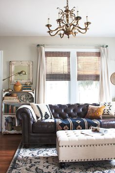 a living room with a couch, ottoman and chandelier hanging from the ceiling