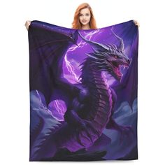 a woman holding up a purple and black dragon blanket with lightning in the sky behind her