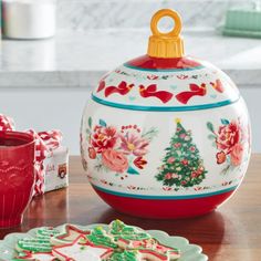 a decorated cookie jar sitting on top of a table next to a cup and plate