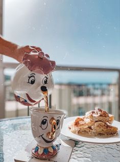 a person pouring coffee into a cup on top of a table next to a pastry