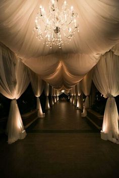 an image of a wedding venue with white drapes and chandeliers