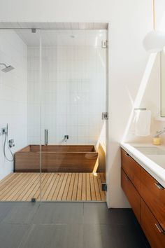 a bathroom with a wooden floor and glass shower door that opens up to the bathtub