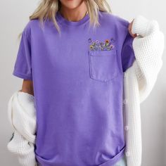 Comfort Colors Embroidered crewneck wildflower pocket tshirt. Embroidered flower shirt. Flower Boho Shirt. Gift for her or Girlfriend Gift. PLEASE NOTE THAT THE PICTURES ON THE LISTING ARE SAMPLES ONLY. If interested in adding embroidery to the sleeve please go to this listing: https://www.etsy.com/listing/1674502020 Because it is made to order, we don't accept the return or exchange unless we make a mistake We are unable to replace or refund purchases based on the color and the font selections. Please make sure to be very specific and make the correct selections when you place an order. Please feel free to reach out to us with any questions. We will do our best to make sure that you are completely satisfied with your order. PRODUCT INFORMATION: 6.1 oz./yd² (US), 10.2 oz/L yd (CA), 100% ri Spring T-shirt With Pockets And Relaxed Fit, Summer Graphic Tee With Pockets, Casual Floral Embroidery Short Sleeve T-shirt, Purple Short Sleeve Tops With Pockets, Summer Crew Neck T-shirt With Floral Applique, Summer Floral Applique T-shirt With Crew Neck, Summer Crew Neck T-shirt With Pockets, Summer Floral Applique Crew Neck T-shirt, Floral Applique Crew Neck T-shirt For Summer