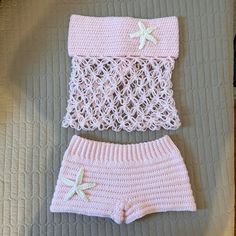 two pieces of pink knitted clothing sitting on top of a bed