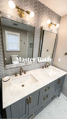 a bathroom with two sinks and mirrors on the wall above them is decorated in gray and gold