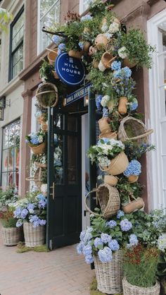 a building with flowers and baskets hanging from the side of it's front door