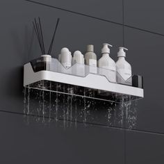 a shower head with soap and lotion on it in front of a gray wall