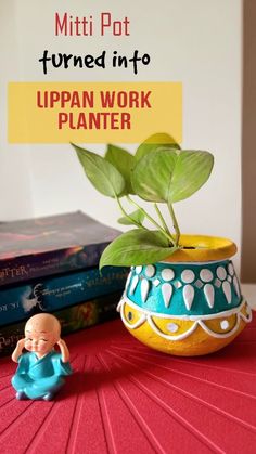 a potted plant sitting on top of a table next to books and a small figurine