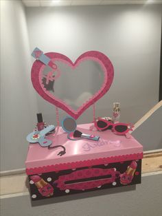 a heart shaped mirror sitting on top of a pink box with other items inside it