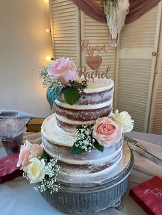 a three tiered wedding cake with flowers on the top is sitting on a table