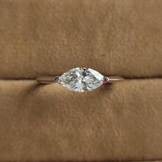 a diamond ring sitting on top of a brown cushion