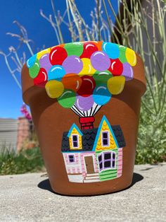 a potted plant with a house and balloons painted on it