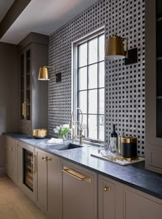 a kitchen that has some lights on above the sink and counter top in front of a window