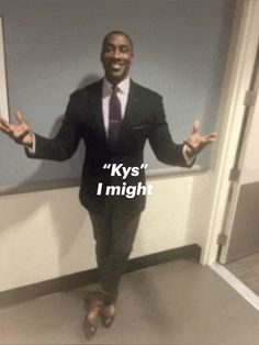 a man wearing a suit and tie standing in front of a door with his hands out