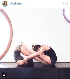 a woman sitting on top of a black table in front of a mirror with her legs crossed