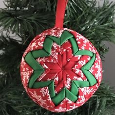 a red and green ornament hanging from a christmas tree with snowflakes on it