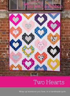 two hearts quilt hanging on the side of a brick building with text overlay that reads two hearts