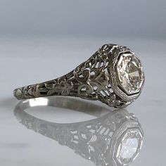 Details: Pretty Edwardian 18K white gold filigree .58 carat diamond ring from the 1920's! The filigree has beautiful sweet flowers in the 18K gold. The height of the ring sits up 5.9mm, and the diamond measures 5.8mm round x 2.78mm deep. Diamond is a VS1, Color J. This ring comes with an appraisal. Please ask all necessary questions prior to placing an order. Details from Appraisal: Cut: Transition/Round Brilliant Cut Carat Weight: .58 carat (estimated) Measurements: 5.8 x 2.78mm Color: J Clarit Formal 14k White Gold Filigree Ring, Victorian Platinum Diamond Ring With Hallmark, Victorian Platinum Diamond Ring Hallmarked, Vintage White Diamond Filigree Ring, Vintage White Filigree Ring With Diamond Cut, Victorian Platinum Filigree Jewelry, White Vintage Filigree Ring With Diamond Cut, Vintage White Round Cut Filigree Ring, Ornate Diamond-cut Filigree Ring