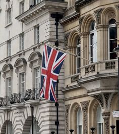 an union jack flag is hanging from a lamp post in front of a large building