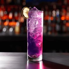 a purple drink with ice and lemon wedges