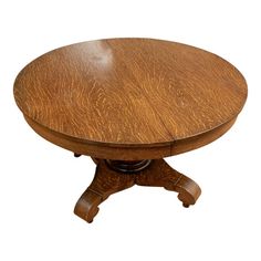 a round wooden table with two leaves on the top and one leaf at the base