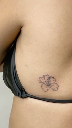 a woman's stomach with a flower tattoo on her left side ribcage