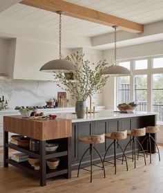 a large kitchen island with stools in front of it and two lights hanging from the ceiling