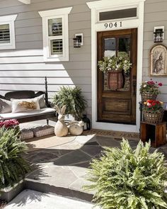 the front door is decorated with plants and potted plants