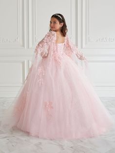 Your sweet girl will love twirling around in this 3D floral applique long sleeveless cape sleeve dress with A-line skirt by Tiffany Princess 13669. This sleeveless V-neck ball gown features detachable cape sleeves, 3D floral appliques throughout the bodice, A-line sparkle tulle skirt, and a lace-up back. House of Wu Tiffany Princess Collection Spring 2022 Style Number: 13669 Fabric: 3D Floral Appliques/ Sparkle Tulle Please note: There may be a loss of glitter while wearing this dress due to the Princess Style Dress With Floral Applique For Debutante Ball, Princess Dress With Floral Applique For Debutante Ball, Princess Style Floral Applique Dress For Debutante Ball, Spring Princess Quinceanera Dresses, Pink Long Sleeve Pageant Dress, Princess Style Long Sleeve Dress For Debutante Ball, Long Sleeve Floral Applique Prom Dress, Pink Long Sleeve Dress For Debutante Ball, Floral Cape