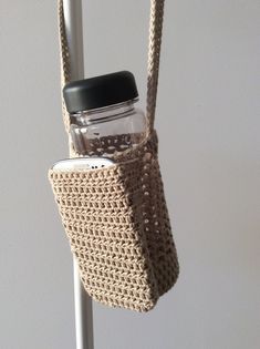 a crocheted bag hanging from a hook with a mason jar in the pocket