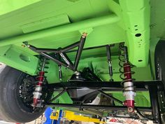 the rear end of a green truck with suspensions