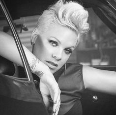 a black and white photo of a woman leaning out of a car window with her hand on the door handle