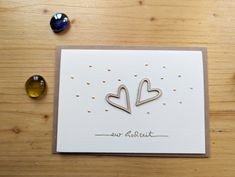 a card with two hearts on it sitting next to some glass beads and other items