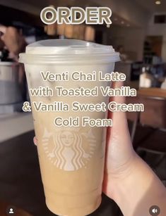 a person holding up a starbucks cup with the words, ventti chai latte with toasted vanilla and vanilla sweet cream cold foam