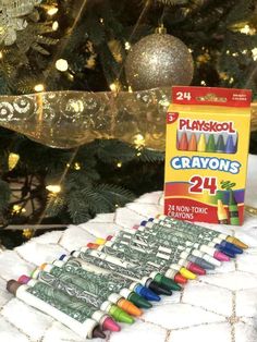 crayons are sitting on a blanket next to a christmas tree and a box of play school crayons