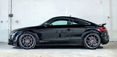 a black sports car parked in front of a white wall