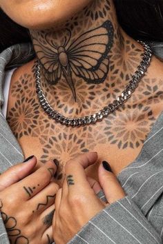 a woman with tattoos on her neck and chest is holding her hands together in front of her chest