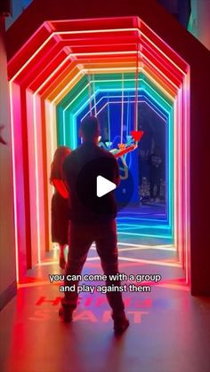 a man standing in front of a colorful light tunnel with the words you can come with a group and play against them