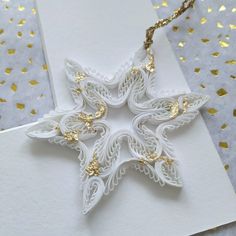 an ornament made out of white paper with gold accents