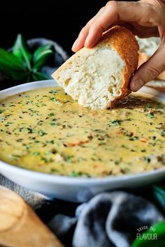 a person dipping bread into a bowl of soup