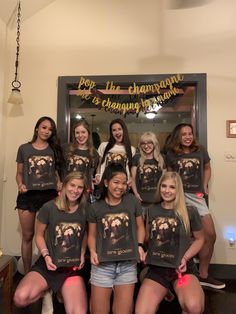 a group of young women standing next to each other in front of a mirror wearing matching shirts