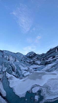 snow covered mountains and water under a blue sky