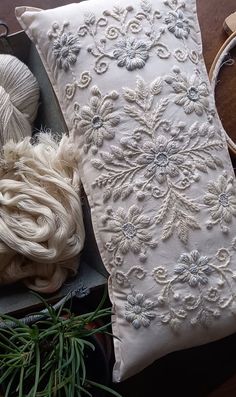 a white pillow sitting on top of a wooden table next to yarn and scissors in a box