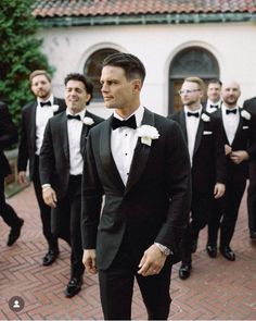 a group of men in tuxedos standing next to each other on a brick walkway